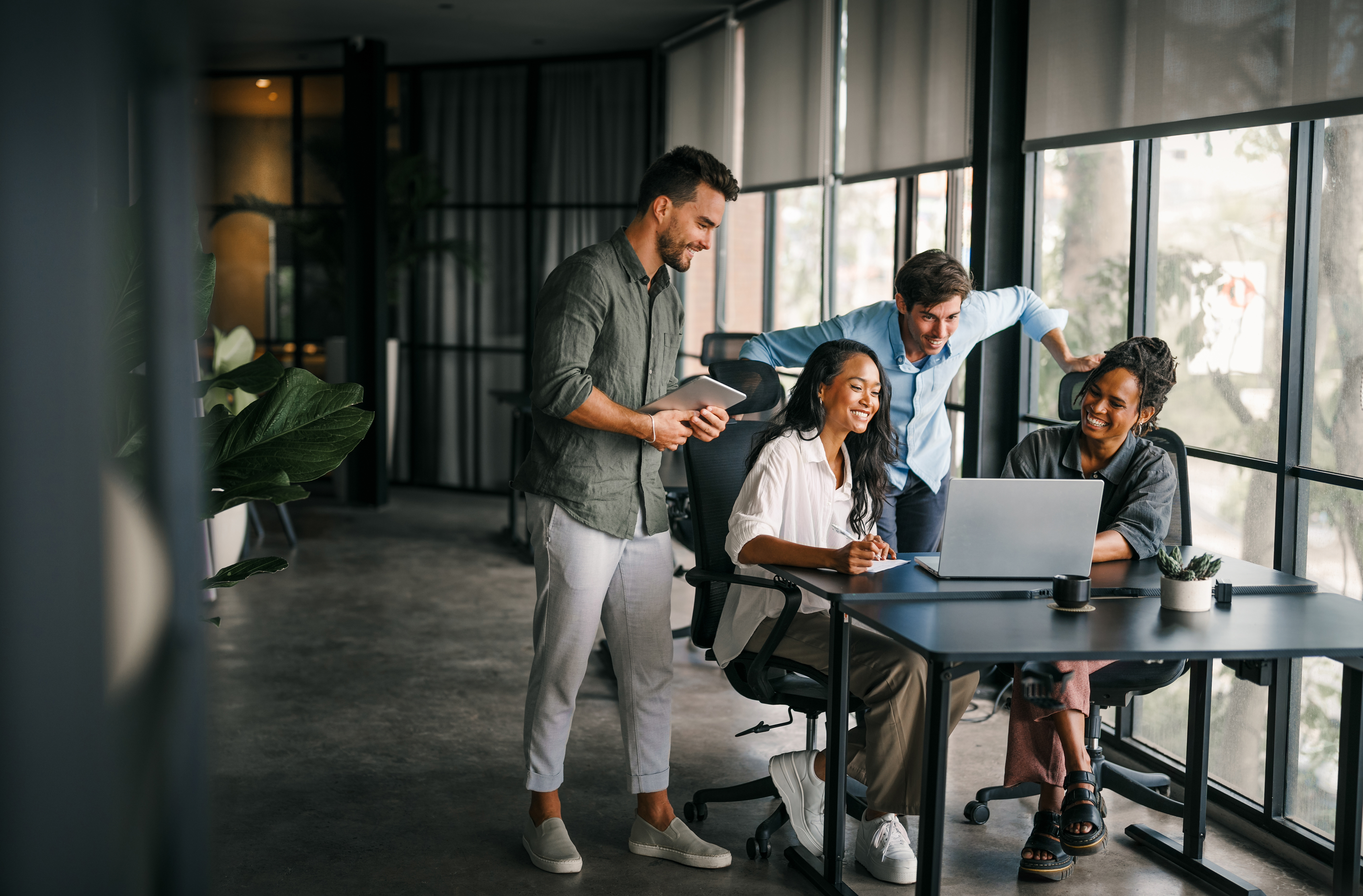 People collaborating around a table talking around a laptop